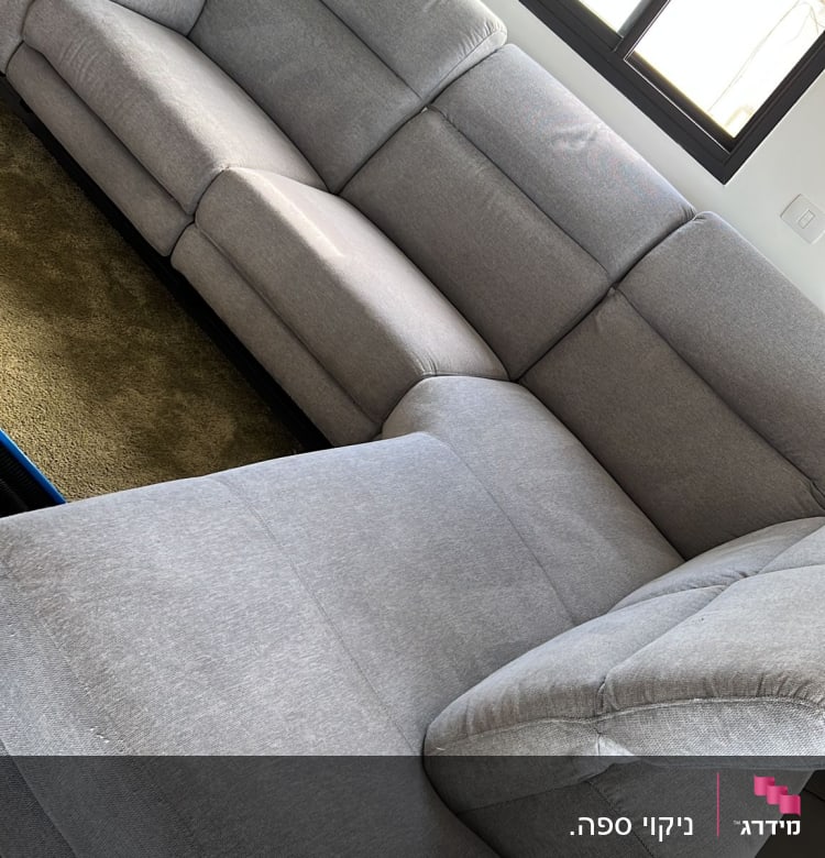 ספה אפורה גדולה ליד חלון עם אור שמש